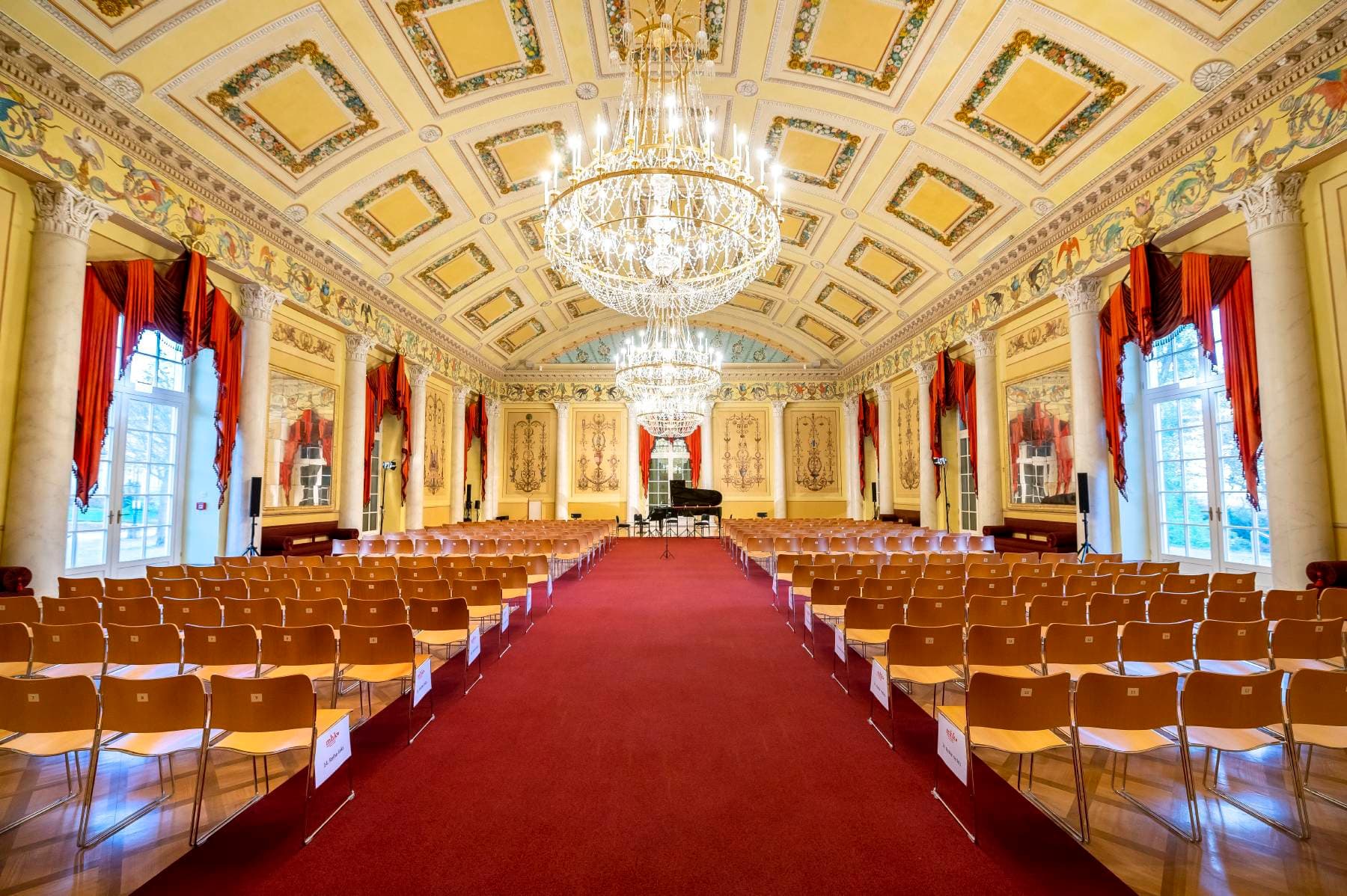 Saal des Ballhauses, mit Bestuhlung und brennenden Kronleuchtern