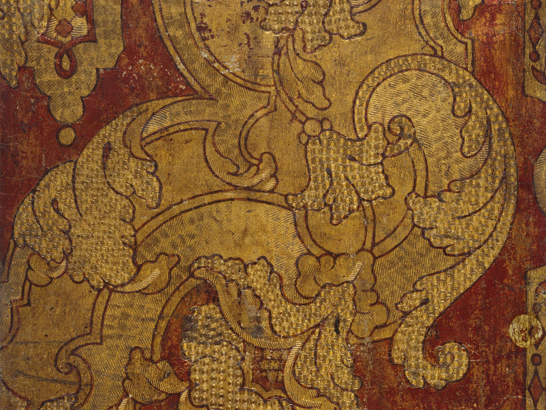 Verzierte Vintage-Tapete in Gold und Rot mit komplizierten Blumen- und Schnörkelmustern sowie strukturierten und gealterten Details.