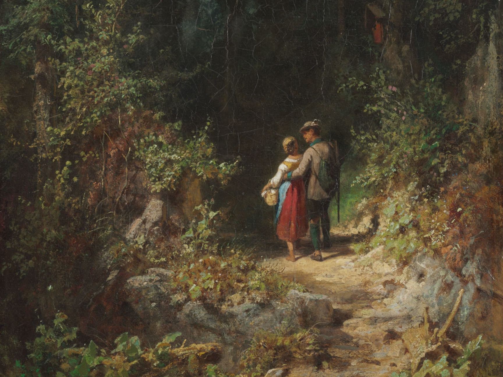 Ein Paar geht Hand in Hand einen Waldweg entlang, umgeben von üppigem Grün und felsigem Gelände, während gesprenkeltes Sonnenlicht durch die Bäume fällt.