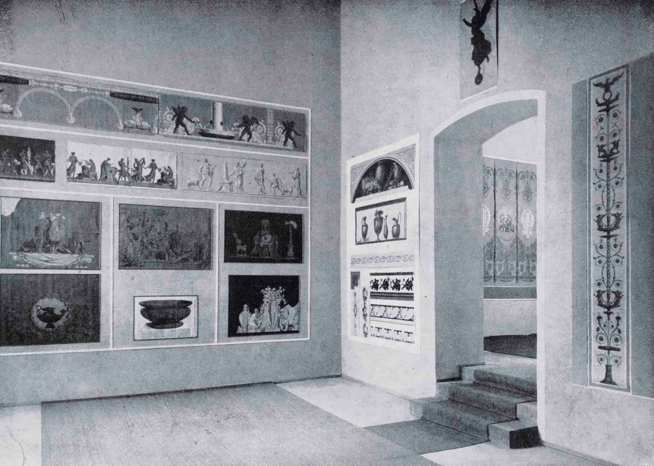 Innenraum einer Kunstgalerie mit gerahmten klassischen Kunstwerken an den Wänden, einem Torbogen, der zu einer Treppe führt, und aufwendigen Wanddekorationen.