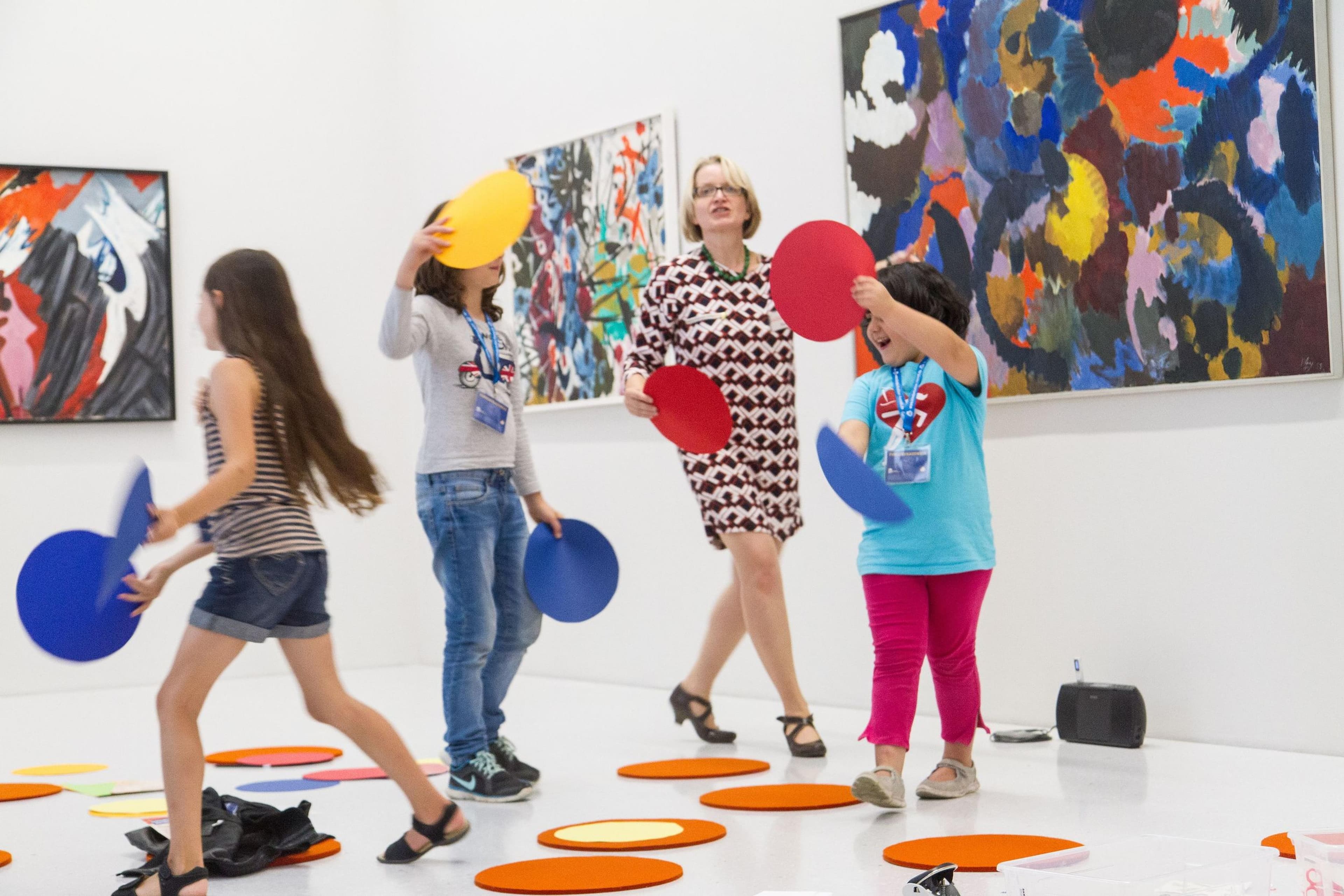 Kinder spielen vor Abstrakten Gemälden mit bunten Kreisen.