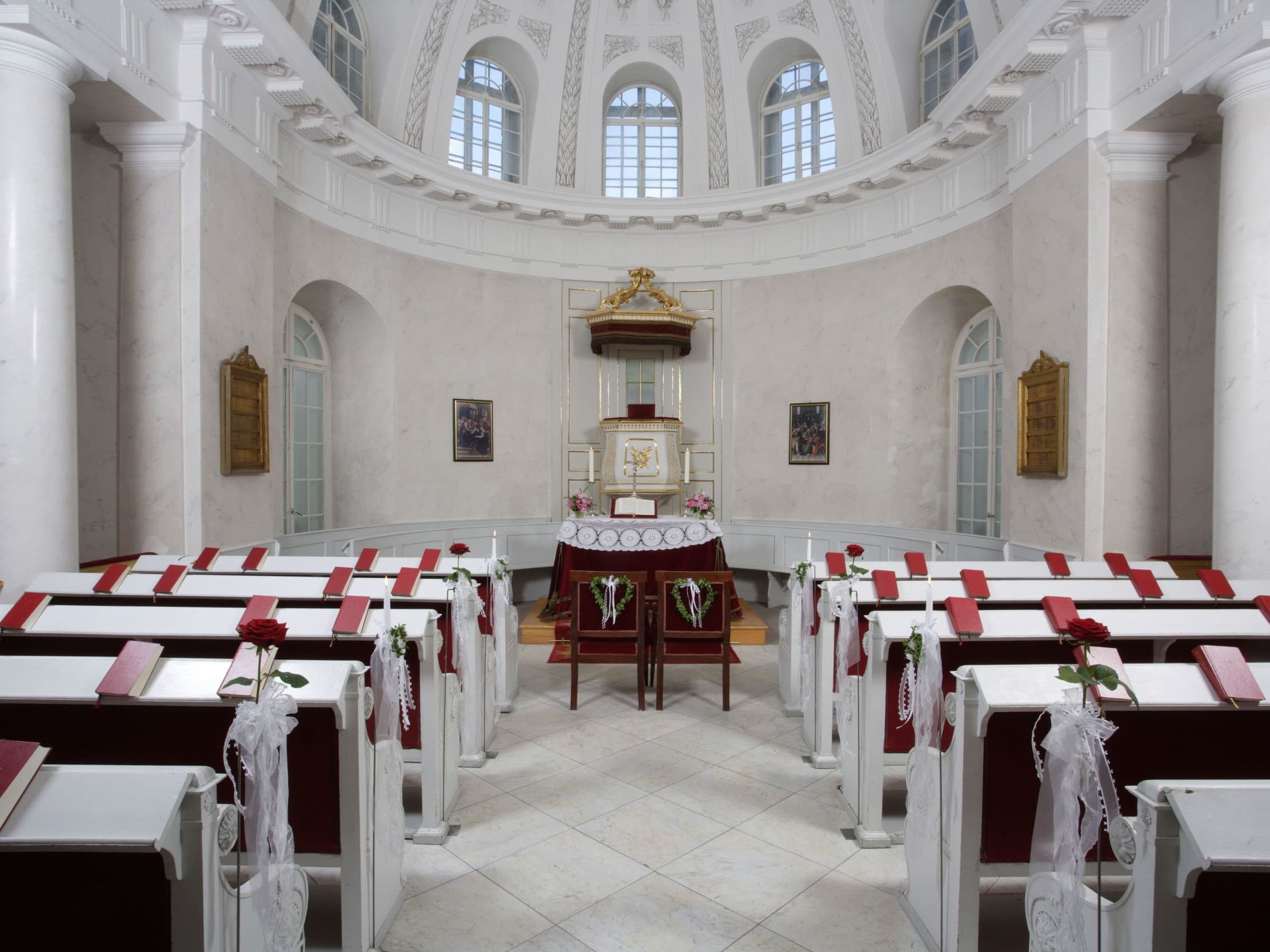 View through the pews to the chancel, in front of which there are two chairs for the bride and groom