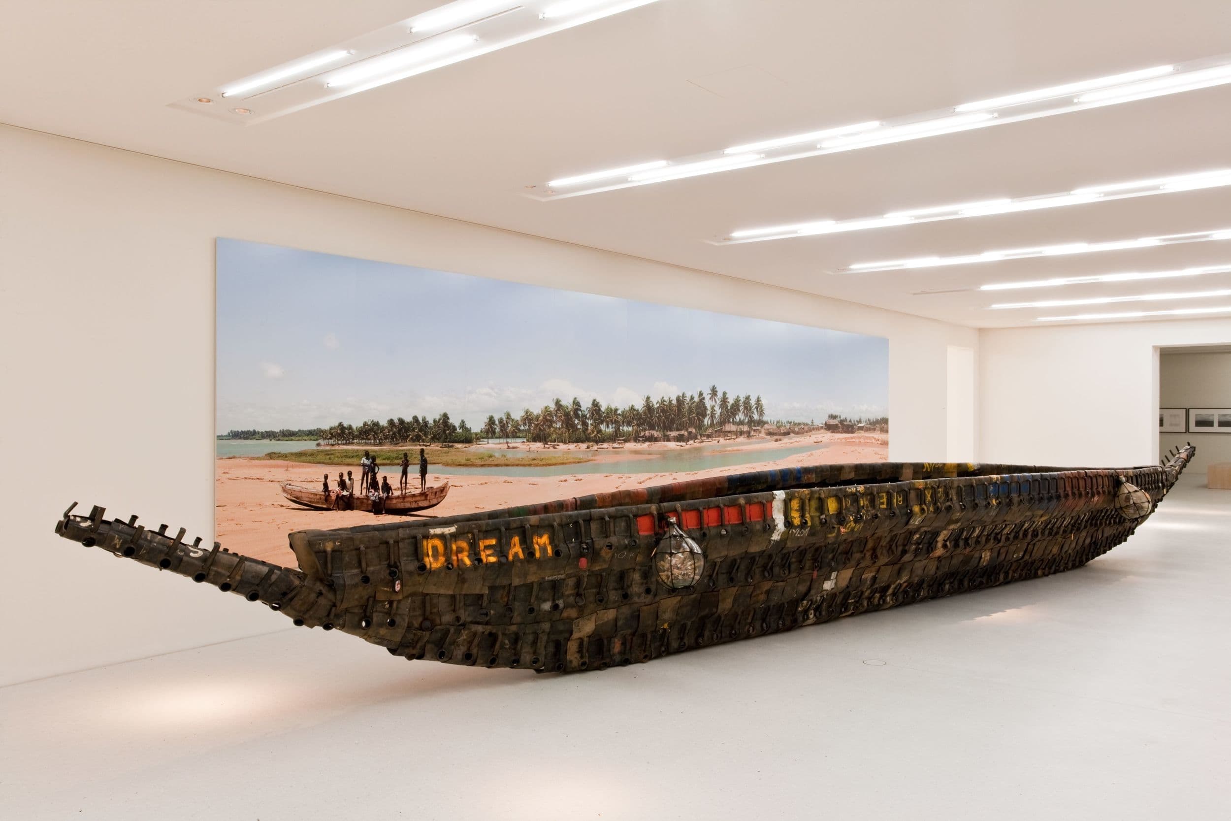 Installation made of various media, consisting of a boat built from oil canisters, 4 glass bottles filled with letters and a large photo