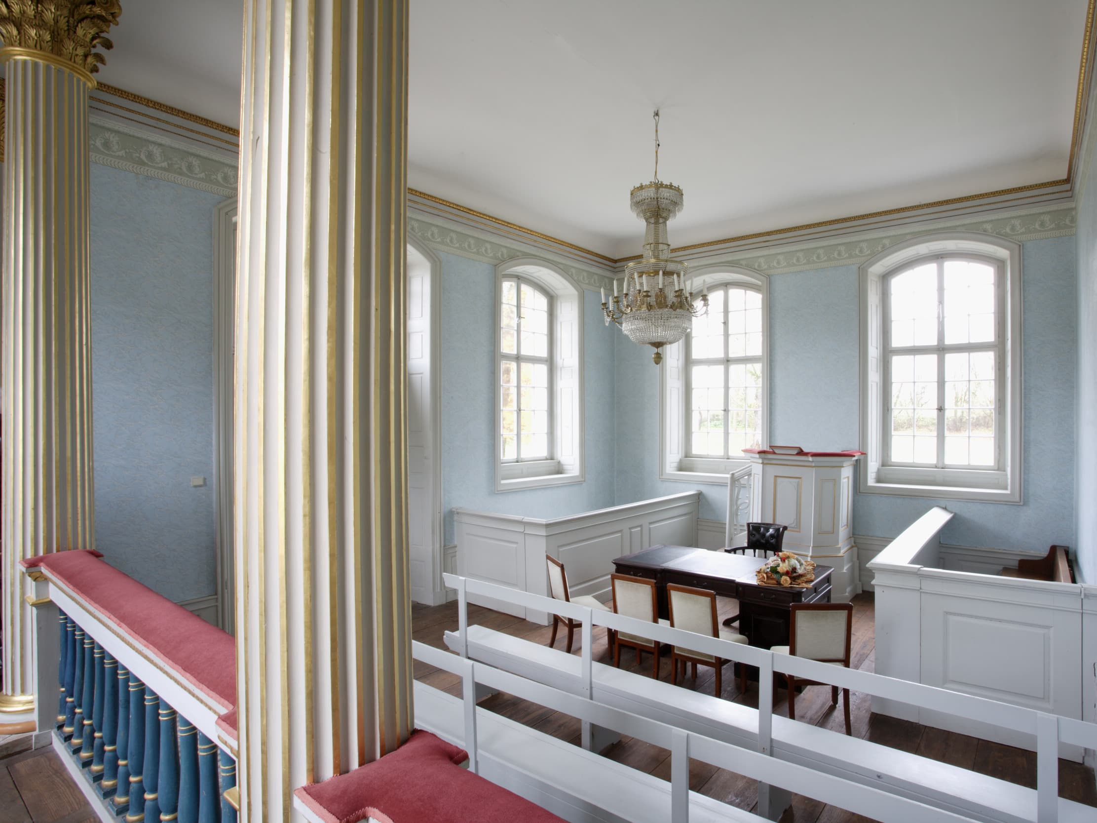 View of the small chapel with white pews, a small pulpit and a table and chairs for wedding ceremonies