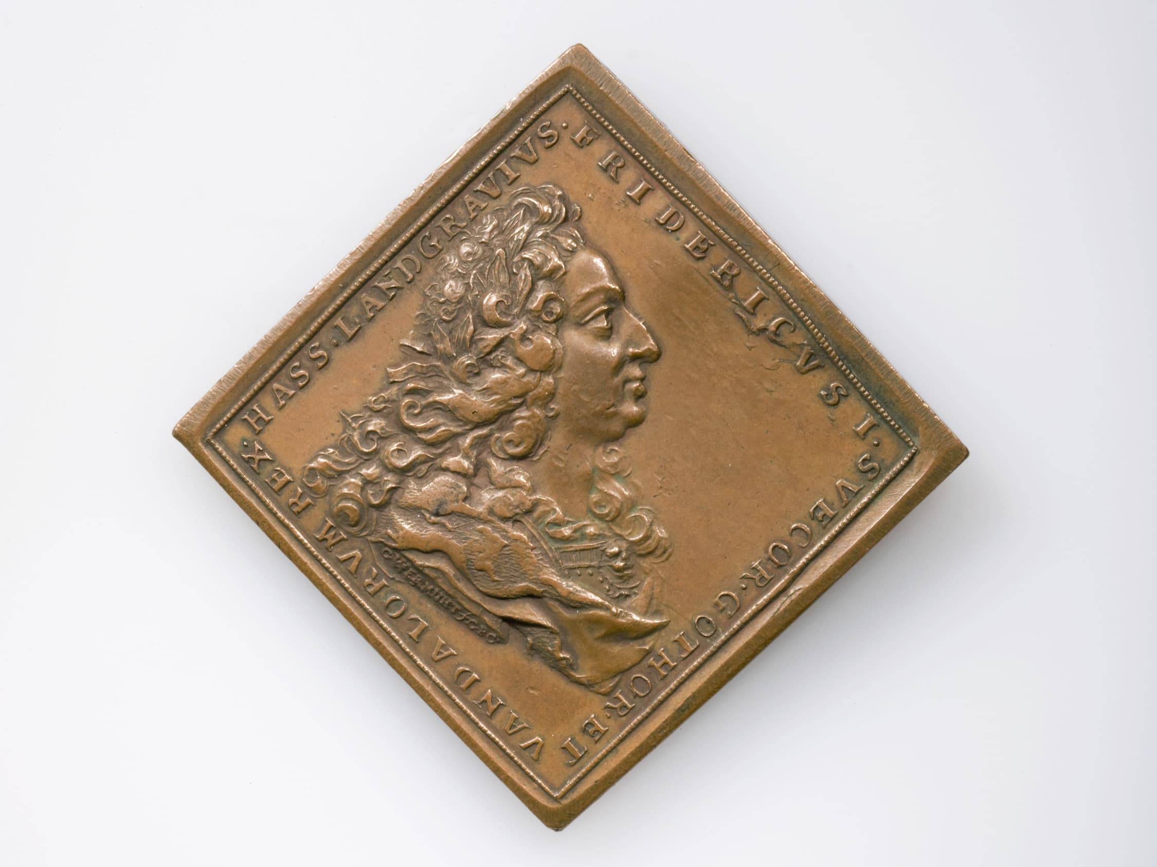 Bronzemedaillon mit dem Profil eines Mannes mit lockigem Haar, beschriftet mit lateinischem Text, rautenförmig auf weißem Hintergrund angeordnet.