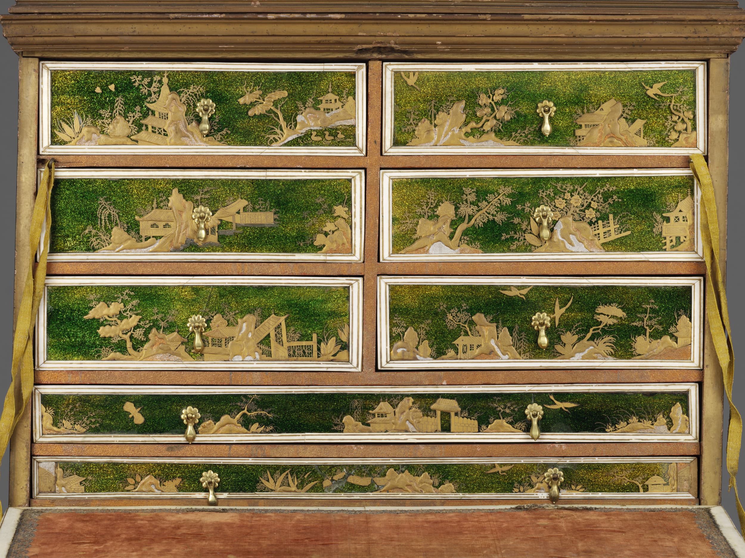 Ein antiker Schrank mit komplizierten grünen und goldenen Landschaftsszenen auf den Schubladen, die Häuser, Bäume und Berge zeigen, mit Messinggriffen.