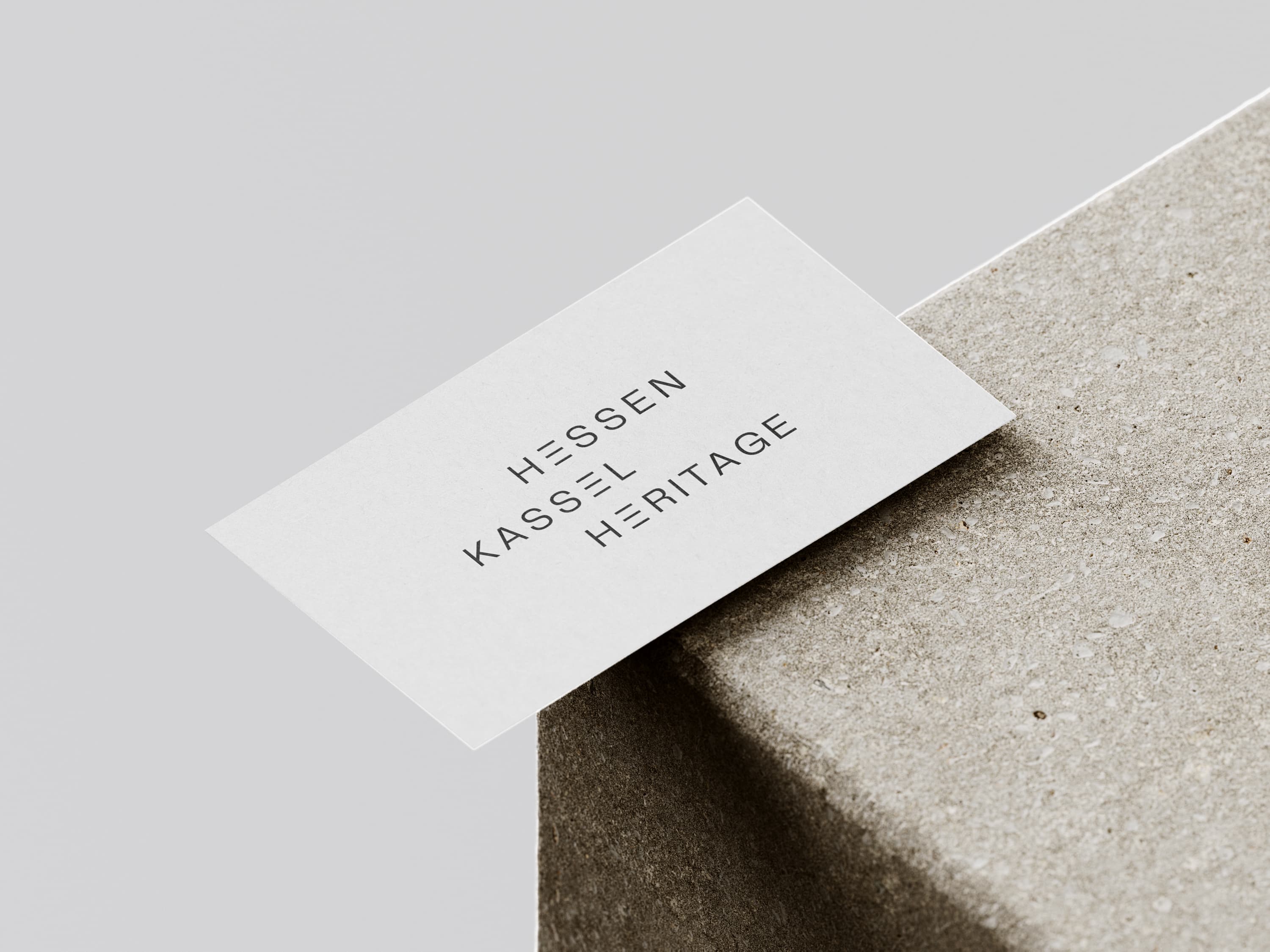 Auf einer strukturierten, grauen Oberfläche liegt eine Visitenkarte mit der Aufschrift „Hessen Kassel Heritage“.