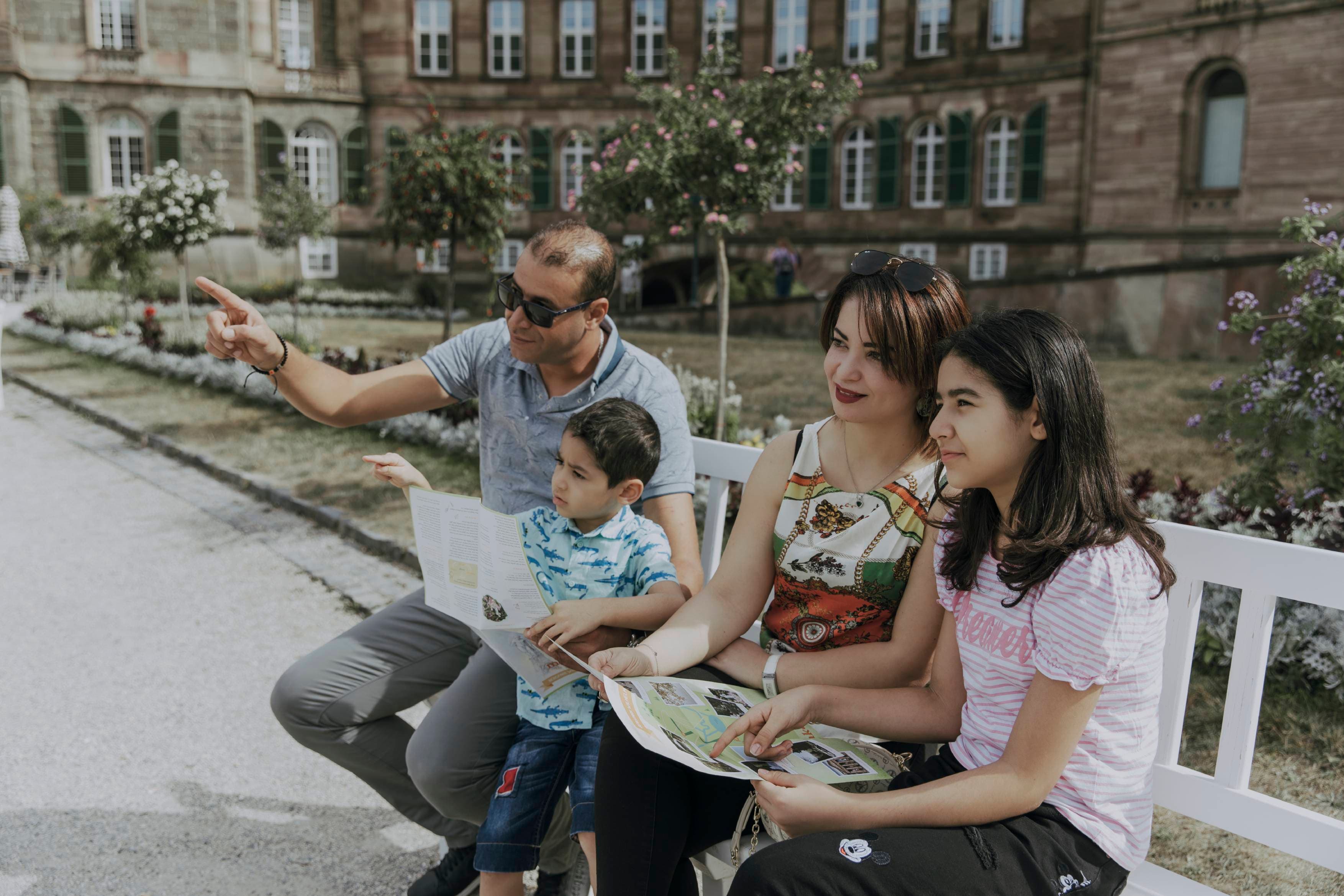 Vierköpfige Familie, die auf einer Bank im Bergpark vor Schloss Wilhelmshöhe sitzt