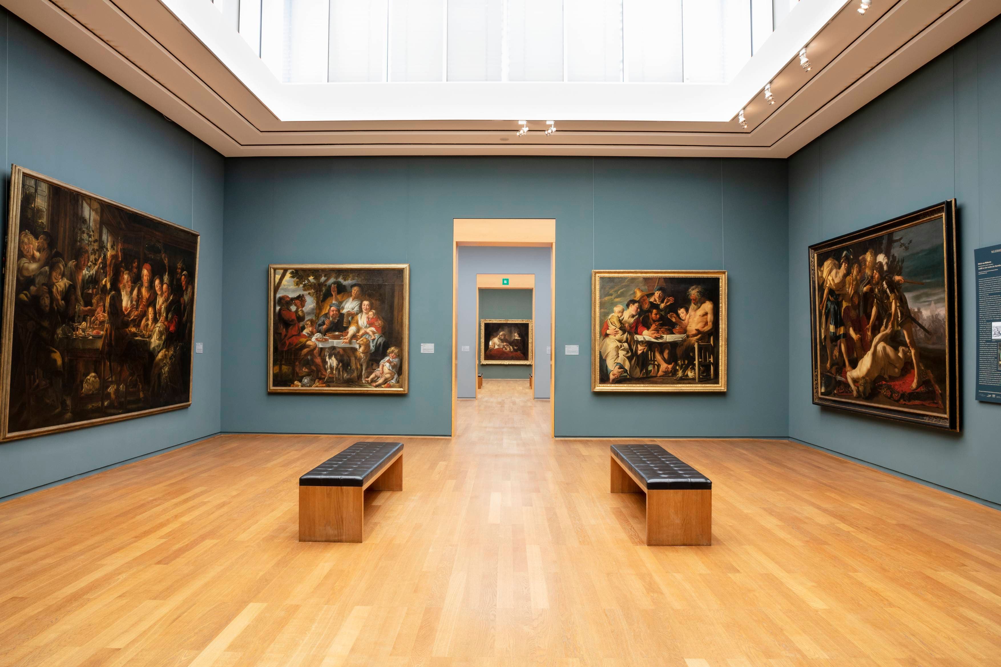 Innenansicht eines Raumes der Gemäldegalerie Alte Meister, im dem vier großformaige Genre-Gemälde hängen und zwei Bänke stehen.
