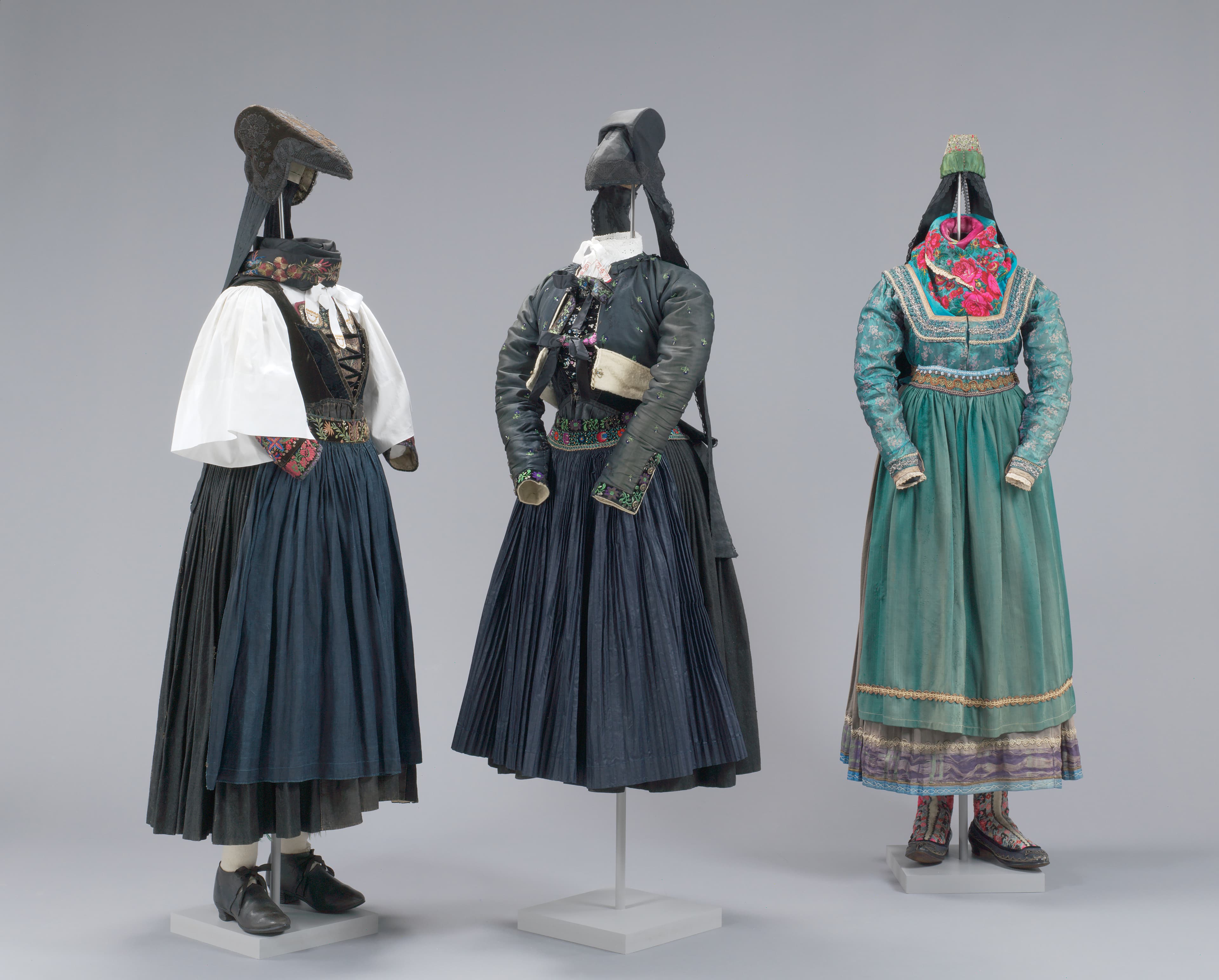 Drei Figurinen, die verschiedene Trachten tragen: Dellmutschentracht,  Schniepenkappentracht und Sonn- und Feiertagstracht für Mädchen