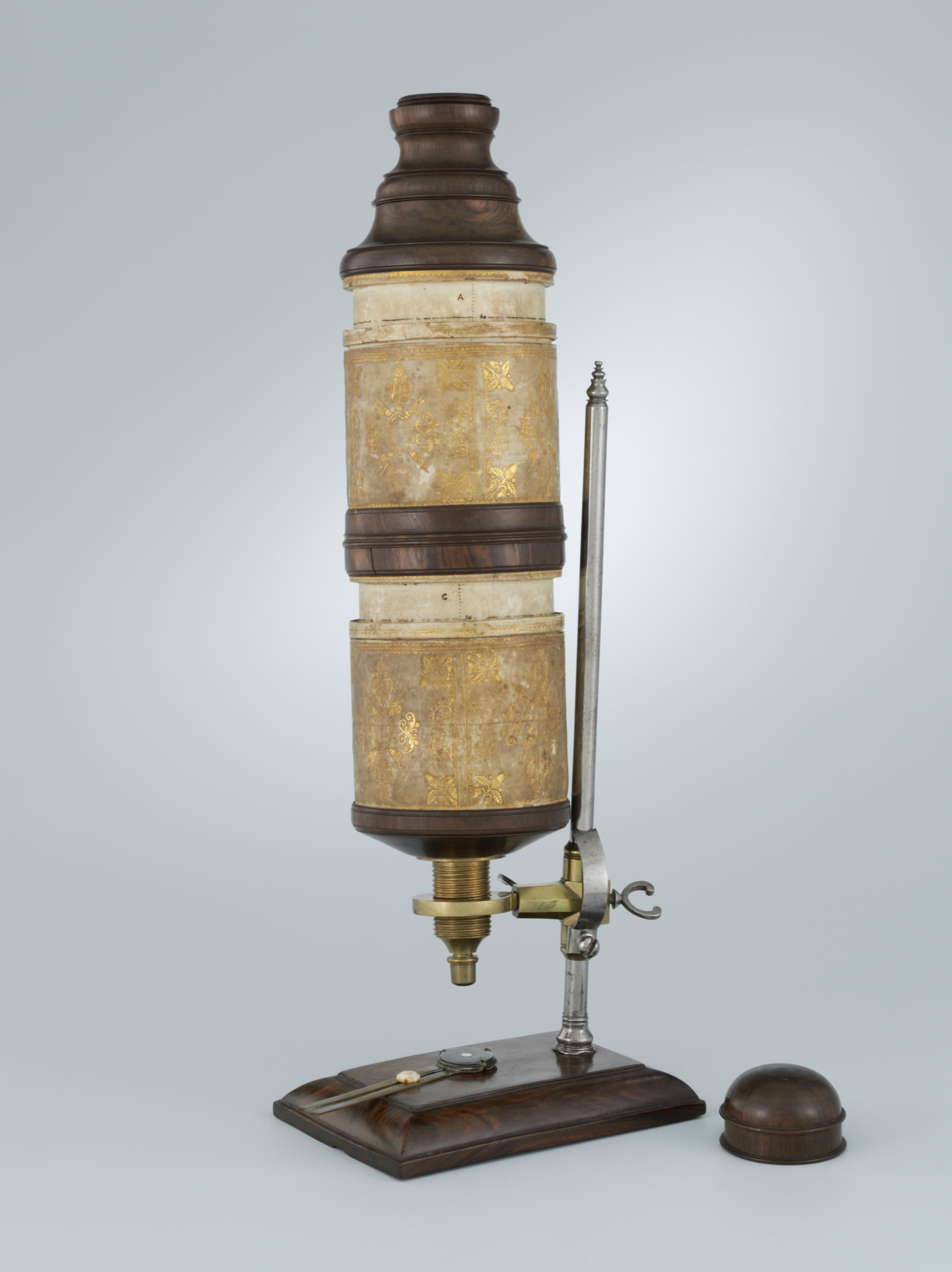 A vintage microscope with a wooden base and body, featuring brass fittings and ornate details, against a light grey background.